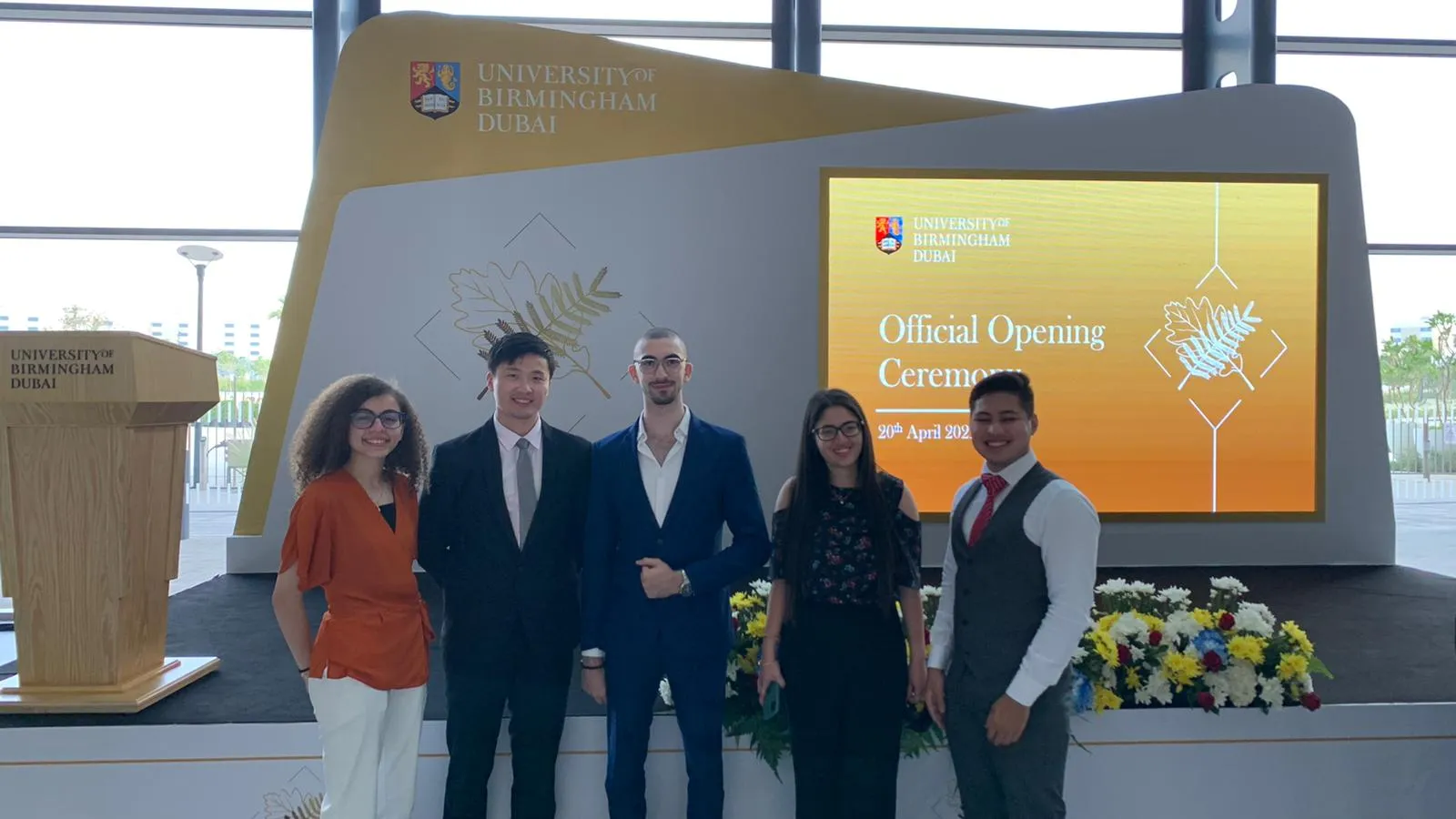 The five members of the student association team standing in front of the stage at the University of Birmingham Dubai’s official opening ceremony, which they hosted