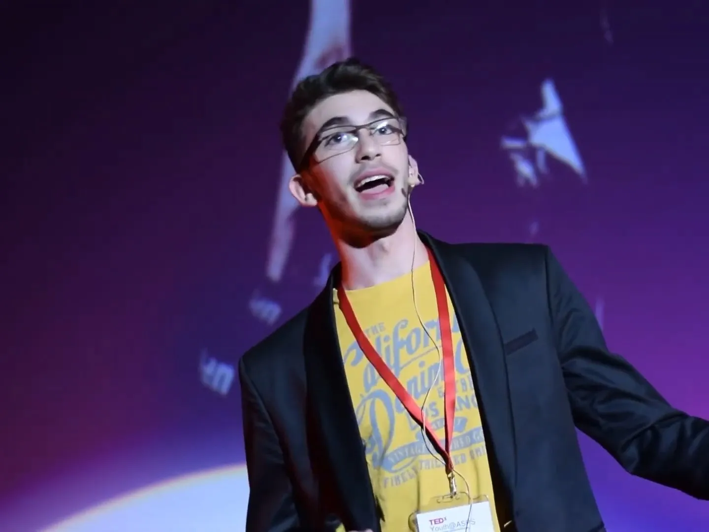 Youssef speaking with arms open at TEDxYouth@ASPS